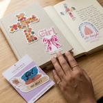 Open book with decorative stickers on a wooden surface next to a mug