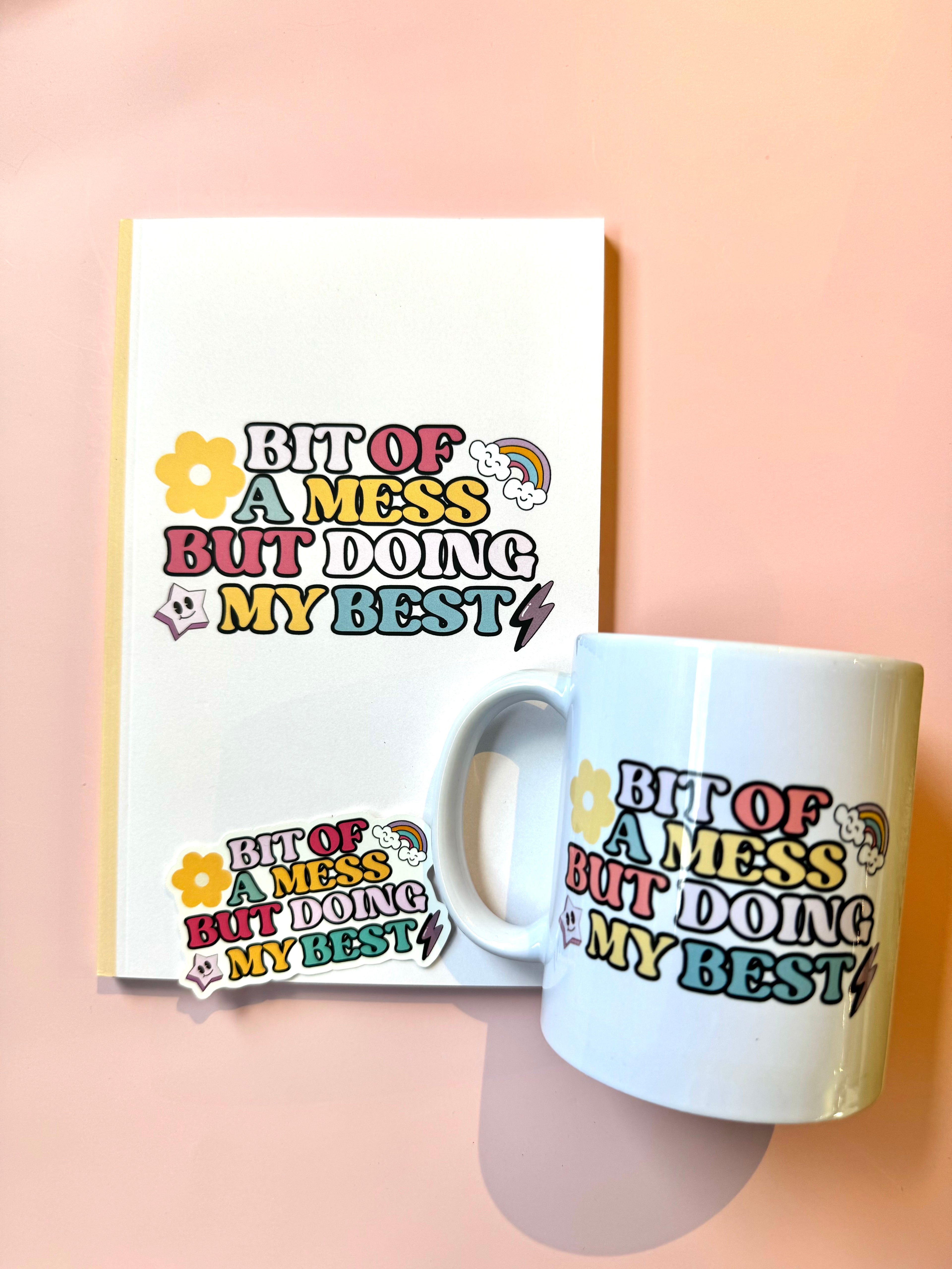 Mug and notebook with 'Bit of a mess but doing my best' text on a pink background