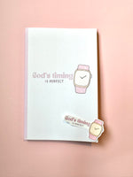 Notebook with 'God's timing is perfect' text and watch illustration on a pink background