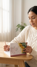 Woman reading a book with a scenic cover in a cozy room.
